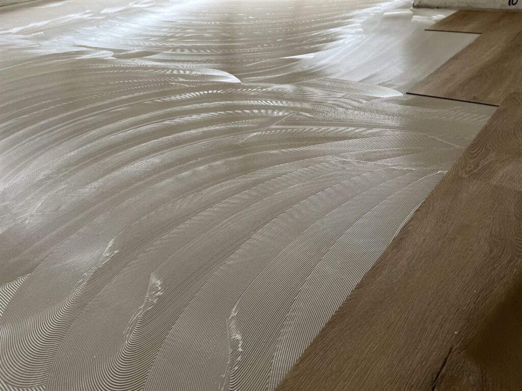 Plak PVC-strook in eikenlook gaat in het lijmbed
