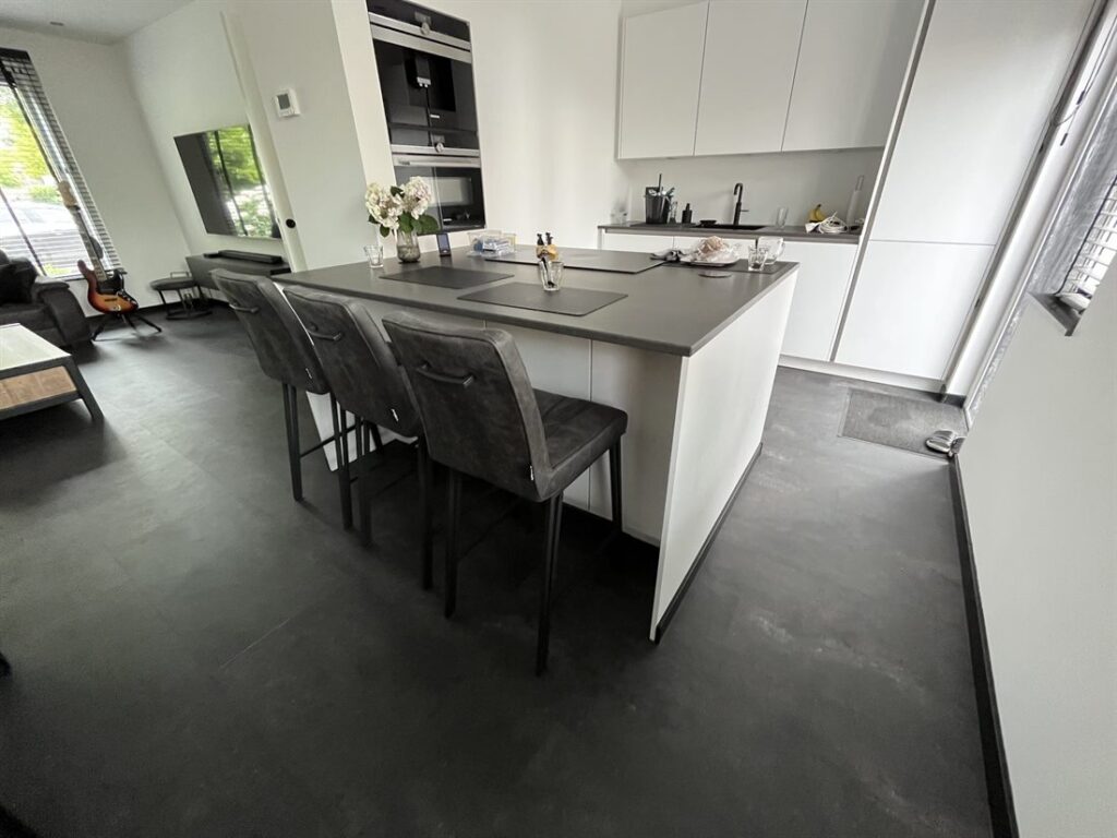 Keuken met kookeiland op een PVC-vloer in donkere betonlook