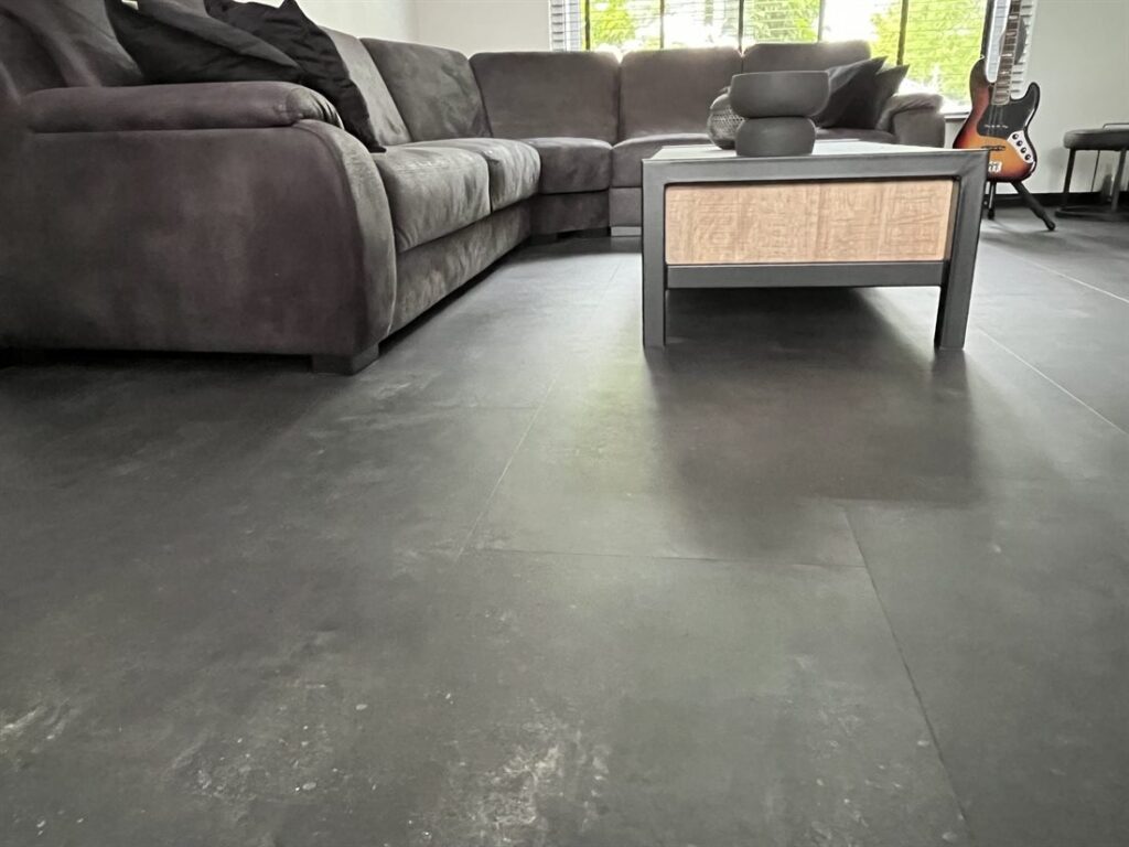 Donkere PVC-vloer in betonlook in een woonkamer met hoekbank
