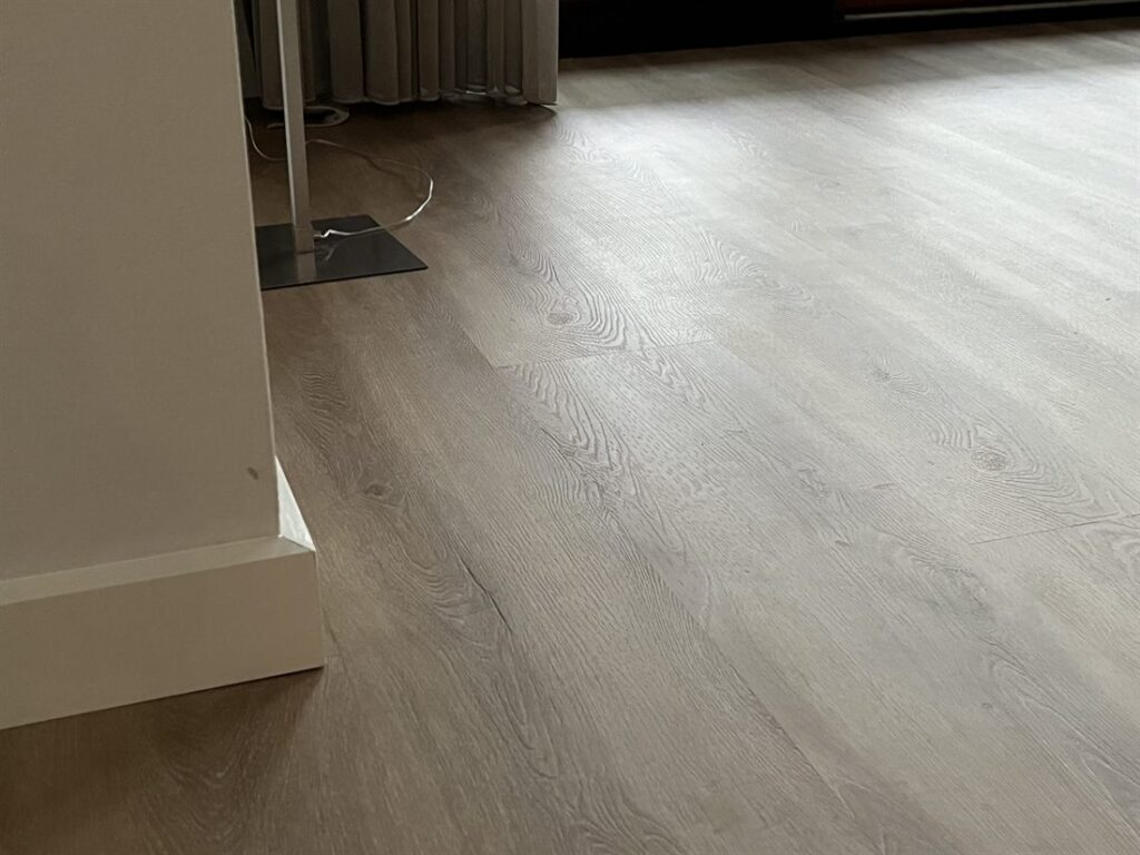 Detail van een PVC-vloer in eikenlook met strak afgewerkte plint