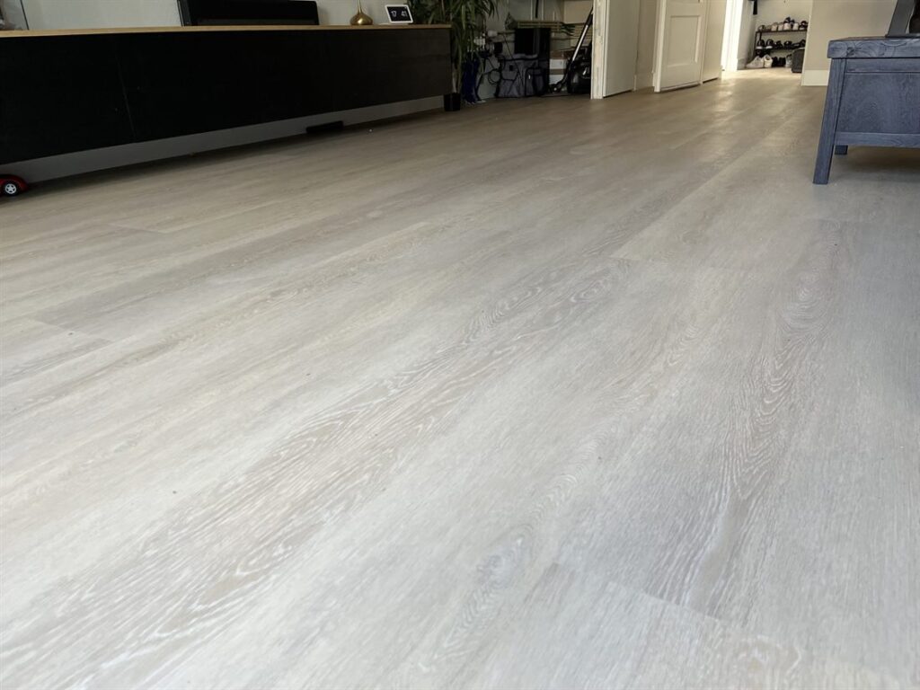 Lichte PVC-vloer met planken in grijze eikenlook in een ruime woonkamer