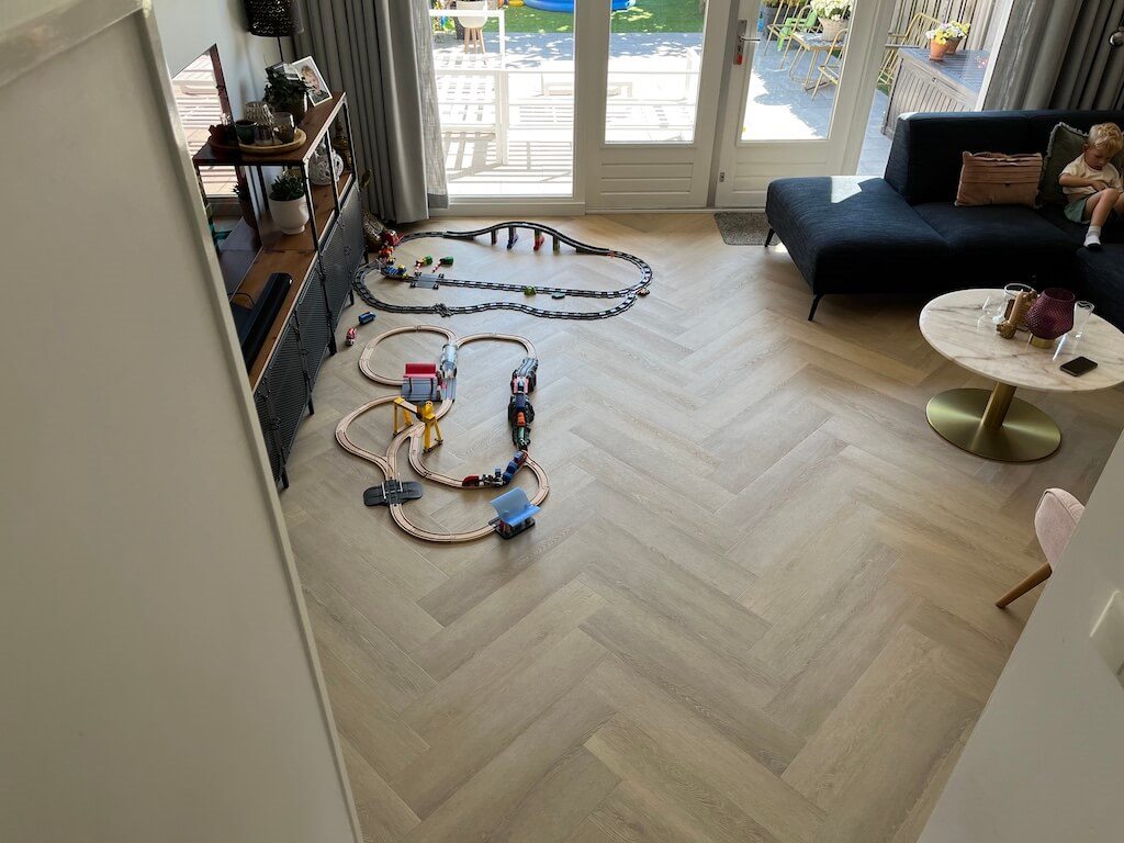 Lichte visgraat PVC-vloer in een gezinswoonkamer met speelgoedtrein
