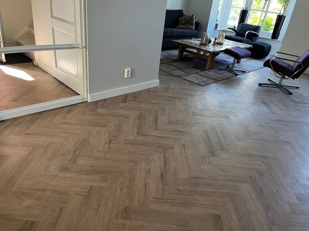 Visgraat PVC-vloer in eikenlook in een woonkamer met bank en salontafel