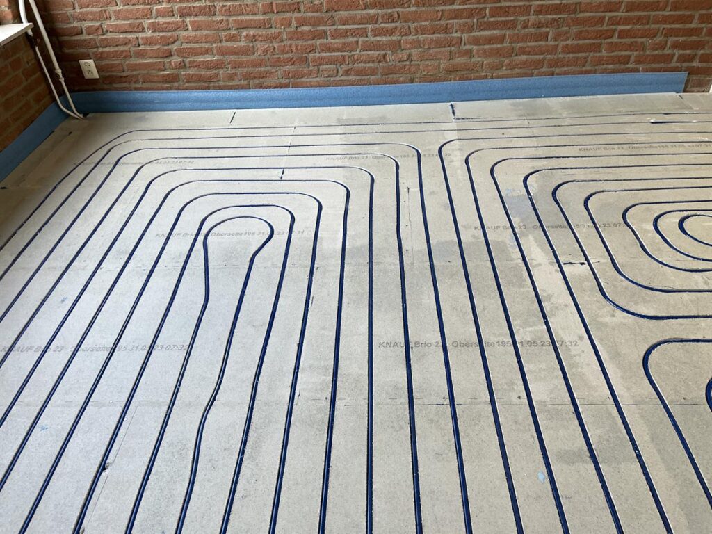 Vloerverwarming ingefreesd in een dekvloer langs een bakstenen muur