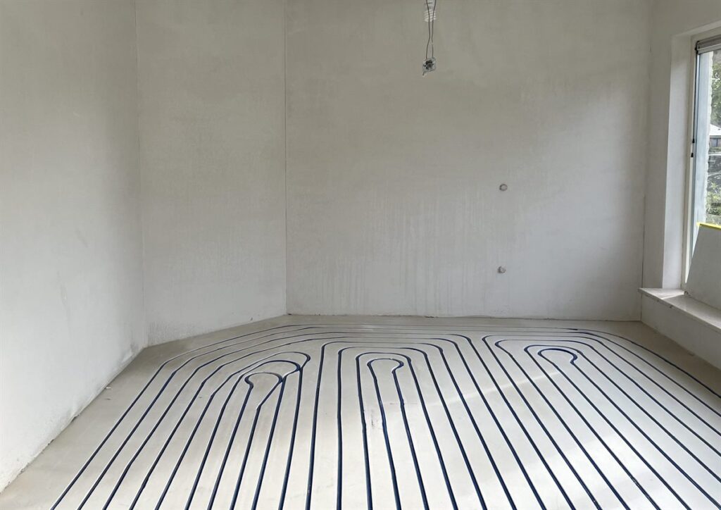 Vloerverwarming ingefreesd in de dekvloer van een lege kamer